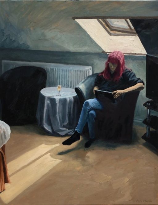 A woman sits in a hotel room reading from a tablet.